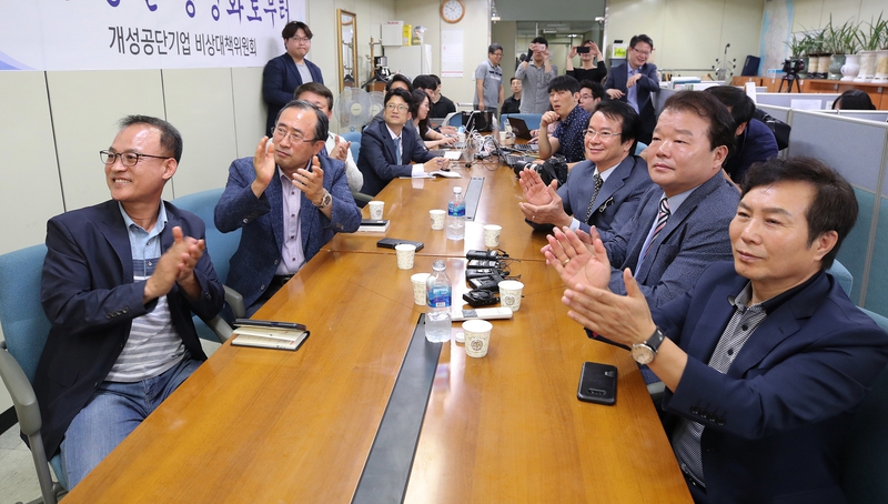 북미 정상회담이 열린 12일 오전 서울 여의도 중소기업중앙회 내 개성공단기업협의회에서 회장단을 비롯한 관계자들이 도널드 트럼프 미국 대통령과 김정은 북한 국무위원장의 역사적인 악수장면을 지켜보며 박수를 치고 있다. 연합뉴스