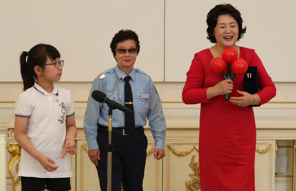 문재인 대통령의 부인 김정숙 여사가 3일 오후 청와대 본관 인왕실에서 열린 사회복지공동모금회 기부자 초청 오찬 간담회에서 공동모금회 명예회장 추대패를 강나연(10)양에게서 받은 뒤 김경자씨가 건네는 공동모금회 ‘사랑의 열매’ 모형을 받으며 활짝 웃고 있다. 김정효 기자