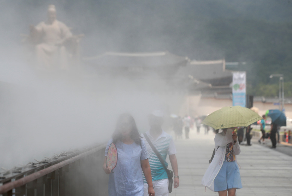 서울 세종대로 광화문광장에 설치된 ‘쿨링 포그(Cooling Fog)‘  주변으로 시민들이 부채와 양산을 들고 오가고 있다. 연합뉴스