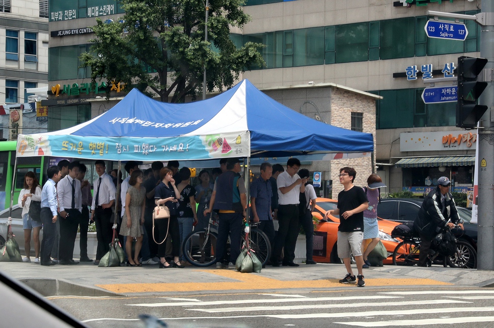 건널목 신호를 기다리는 시민들이 천막 그늘에서 따가운 햇볕을 피하고 있다. 강재훈 선임기자 khan@hani.co.kr