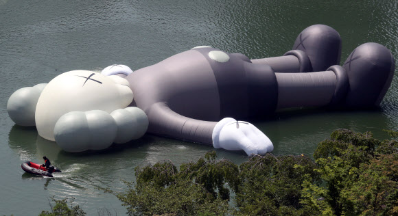 19일 서울 잠실 석촌호수에 세계적인 팝 아티스트 카우스(KAWS)의 공공미술 프로젝트인 ‘‘카우스: 홀리데이 코리아‘‘ 작품이 전시돼 관계자가 작품을 점검하고 있다. 이 작품은 세로 28M, 가로 25M, 높이 5M로 독창적인 캐릭터를 활용해 일상으로 부터 탈출해 모든 것을 잊고 세상을 바라보며 휴식을 취하는 모습을 표현하고 있다.  연합뉴스