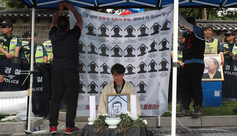 지난 3일 서울 중구 대한문 앞에 설치된 쌍용자동차 해고노동자 고 김주중씨 분향소에서 김득중 금속노조 쌍용차지부장이 상복 차림으로 김씨의 영정을 들고 참배객의 조문을 받고 있다. 박종식 기자 anaki@hani.co.kr