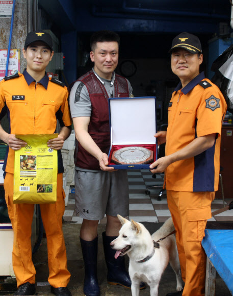 26일 오전 광주 북구 말바우시장에서 지난 22일 시장 내에서 화재가 발생하자 짖어 알린 견공에게 광주 북부소방서 대원들이 표창장을 수여하고 있다. 2018.7.26 연합뉴스