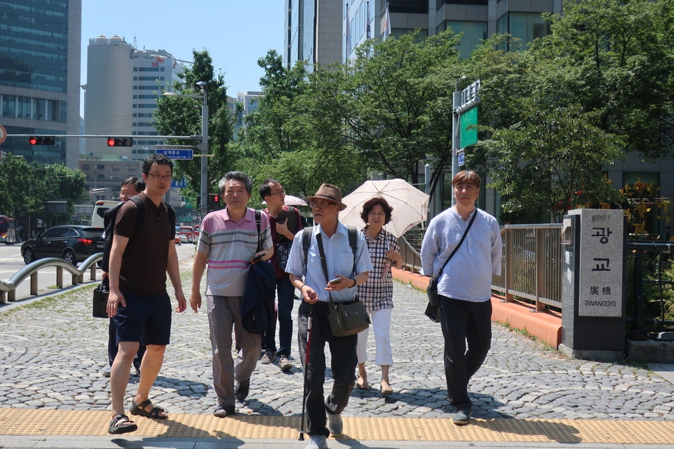 소설가 구보 박태원의 차남인 박재영씨(지팡이 짚은 이)가 1일 낮 서울 청계천 광교를 건너며 부친의 소설 ‘소설가 구보씨의 일일’에 관해 설명하고 있다.