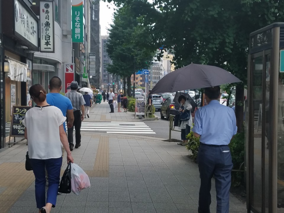 지난달 24일 일본 도쿄 주오구 거리에서 한 남성이 커다란 양산을 들고 걸어가고 있다. 도쿄/조기원 특파원