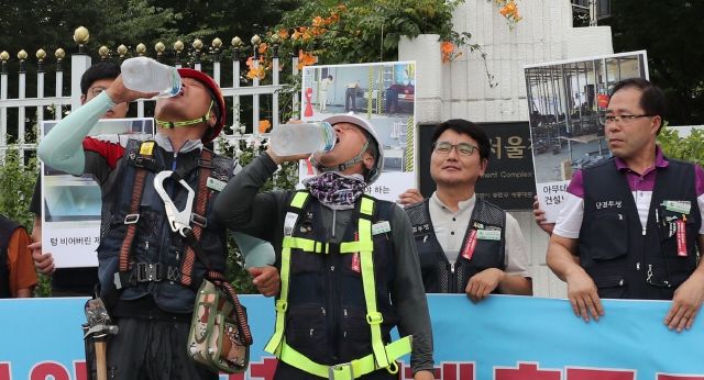 지난달 24일 오전 서울 세종로 정부서울청사 앞에서 열린 ‘건설현장 폭염 안전규칙 이행 촉구 기자회견’에 참석한 건설노동자들이 기자회견 도중 물을 마시고 있다. 백소아 기자 thanks@hani.co.kr