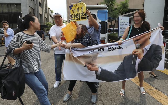 8월14일 서울서부지법 앞에서 한 여성이 안 전 지사를 지지하는 사람의 펼침막을 뺏으려 하고 있다. 연합뉴스