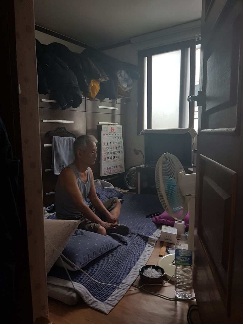 23일 충남 천안시에 사는 홀몸노인 이태권(가명·70)씨가 창문을 열어놓은 채 방에 앉아 있다. 이씨는 두 차례 다리 수술을 받아 거동이 불편하다.