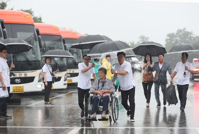 제21차 이산가족 상봉행사 2회차 첫날인 24일 오전 강원도 속초시 한화리조트에서 상봉대상자와 가족들이 우산을 쓴 채 버스로 향하고 있다. 연합뉴스