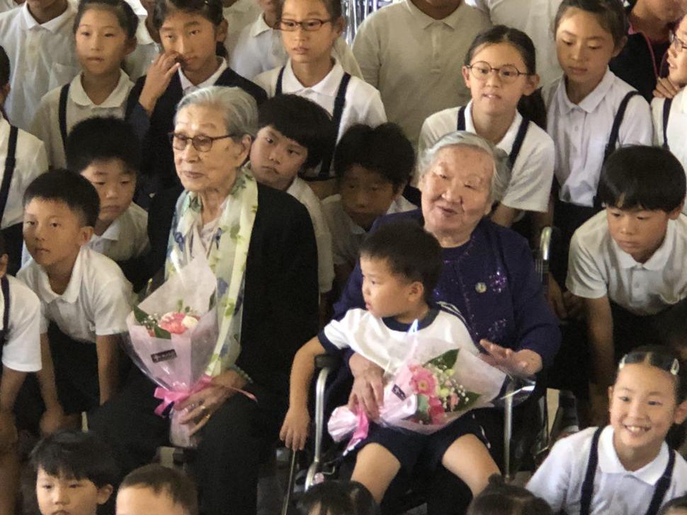 일본군 위안부 피해자 김복동·길원옥 할머니가  28일 오전 일본 오사카 조호쿠 조선초급학교를 찾아 태풍 피해를 입은 학교 학생들을 위로한 뒤 함께 사진을 찍고 있다. 정의기억연대 제공