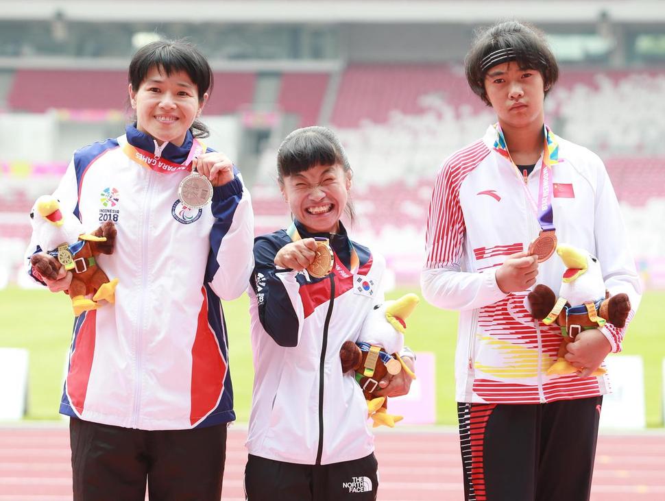 2018 인도네시아 장애인아시아게임 육상에서 2회 연속 2관왕에 오른 전민재(가운데)가 10일 육상 여자 200m(T36) 시상식에서 금메달을 목에 걸고 환한 미소를 짓고 있다. 전민재는 200m(T36)에 이어 100m(T36)에서도 금메달을 목에 걸며 대회 2관왕에 올랐다. 대한장애인체육회 제공