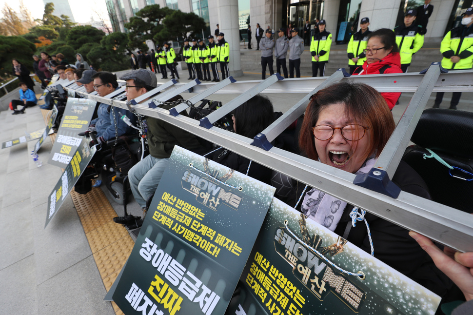 전국장애인차별철폐연대 소속 장애인들이 5일 오후 국회의원회관 앞에서 ‘진짜’ 장애등급제 폐지를 위한 내년도 장애인복지 예산 확대 촉구와 정당 대표자들과의 면담을 요구하며 사다리와 쇠사슬을 목에 걸고 시위를 벌이고 있다. 이들은 장애인활동지원 예산과 장애인연금 예산의 대폭 증액을 요구하고 있다. 강창광 기자