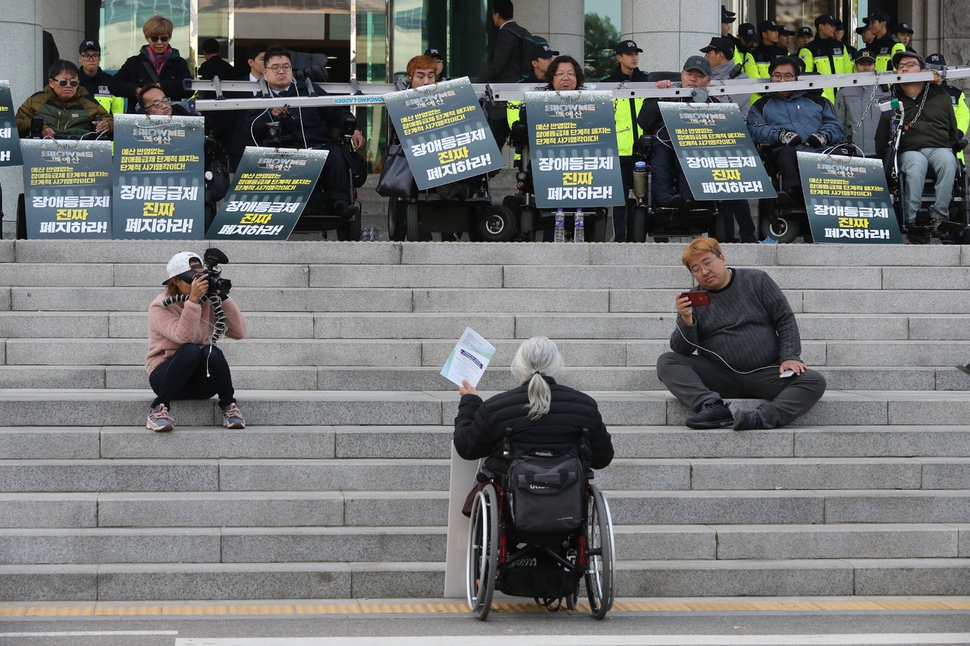 국회의원회관 앞에서 기습시위를 벌이던 장애인들이 더불어민주당 조정식 예결위 간사와 만나고 돌아온 대표자의 설명을 듣고 있다. 강창광 기자