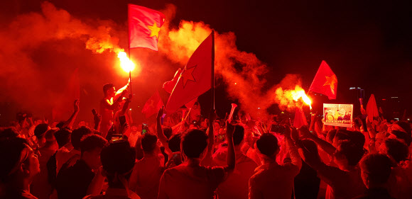 16일 박항서 감독이 이끄는 베트남 축구대표팀이 동남아축구선수권대회 조별리그 2차전에서 말레이시아를 2-0으로 꺾자 베트남 하노이 축구 팬들이 불꽃을 터트리며 환호하고 있다. 응원단이 높이 든 박 감독의 사진이 눈에 띈다.
