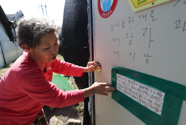 지난달 4일 배광자(78)씨가 경기도 과천 꿀벌마을에 있는 비닐하우스 문 앞에 써둔 안내문을 설명하고 있다. 하루에 한번 지역 복지관에서 기초생활수급자에게 도시락을 전달하는데, 담당자가 혹시나 집 문이 닫혀 있어 그냥 지나칠까 싶어 붙인 글이다. 과천/백소아 기자 thanks@hani.co.kr