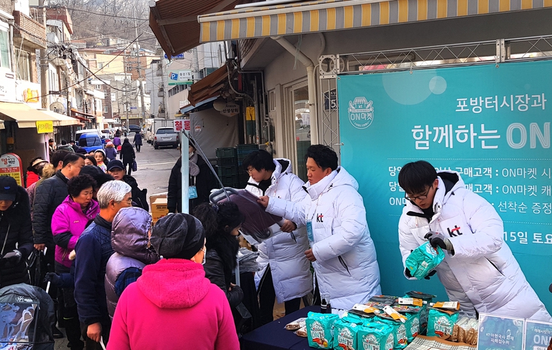 케이티 직원들이 서울 서대문구 포방터시장에서 상인들에게 방한용 조끼와 앞치마를 나눠주고 있다. KT 제공