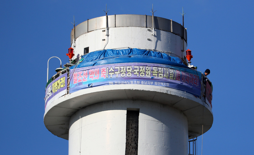24일 오전 서울 양천구 열병합발전소 굴뚝에서 금속노조 충남지부 파인텍지회 홍기탁 전 지회장과 함께 굴뚝 농성을 벌이는 박준호 사무장이 아침 식사를 마친 뒤 용기가 담긴 가방을 줄에 메달아 동료들에게 전달하고 있다. 모회사의 공장 중단과 정리해고에 반발해 차광호 지회장이 2014년 5월 27일부터 2015년 7월8일까지 408일 동안 고공농성을 벌인 뒤 공장 정상화와 단체협약 체결 등의 약속을 받아냈으나, 그 약속이 다시 지켜지지 않자 홍 전 지회장과 박 사무장이 다시 굴뚝 농성에 나섰다. 그리고 이날로 두 명의 노동자가 굴뚝 농성에 돌입한 지 다시 408일째가 되었다.  연합뉴스