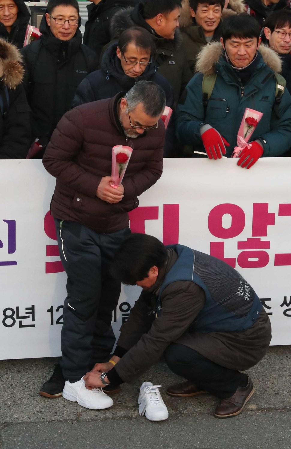 김득중 금속노조 쌍용차지부장이 31일 복직하는 김정우 전 지부장에게 운동화 끈을 매어주며 출근을 축하하고 있다.