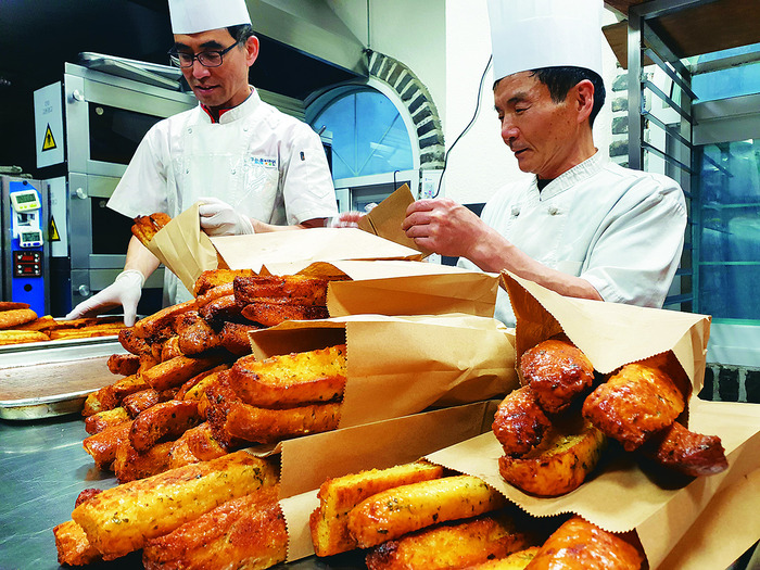 ‘미스터 통밀’의 최양재(사진 오른쪽) 제빵사가 동료 이규홍씨와 ‘마늘스틱’을 담고 있다. 김포그니 기자