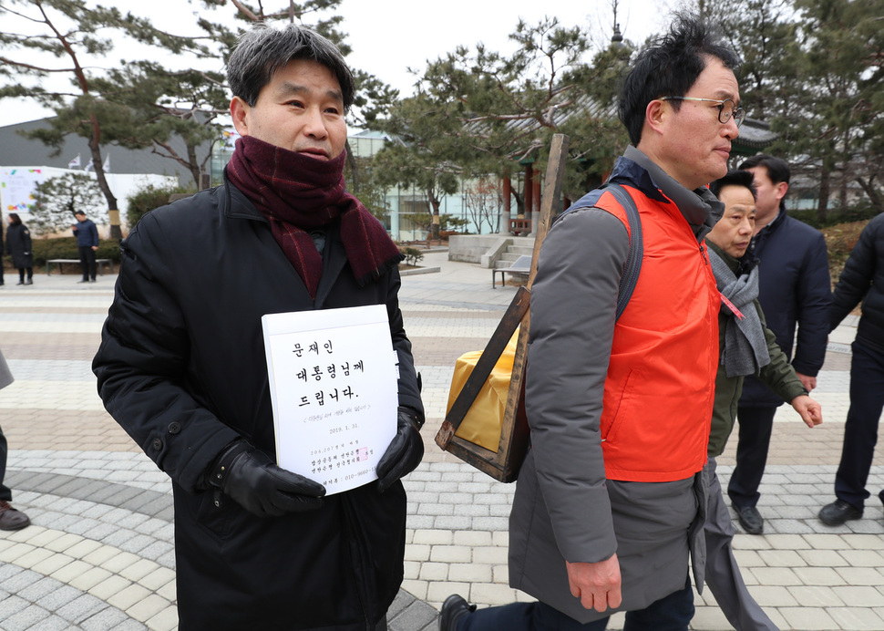 연탄은행 전국협의회와 밥상공동체 연탄은행 관계자들이 31일 오전 서울 종로구 청와대 분수대 앞에서 기자회견을 열어 연탄가격 인하를 촉구한 뒤 20만여 명이 서명한 서명지를 대통령에게 전달하겠다며 연탄지게에 얹고 민원실로 향하고 있다. 김정효 기자 hyopd@hani.co.kr