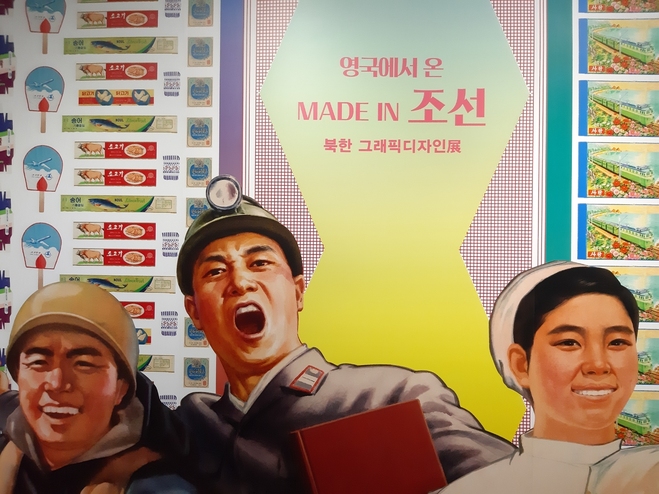 ‘메이드 인 조선’ 전시에 나온 북한 디자인 이미지. 손그림 라벨들을 배경으로 포스터 속 일꾼들 이미지를 확대해 붙인 패널판이다.