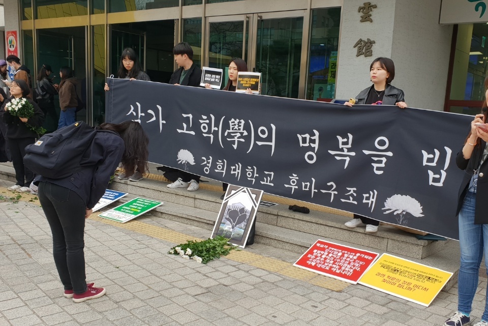 ‘후마니타스 장례식’에 참석한 한 학생이 국화꽃을 놓고 묵념하고 있다.