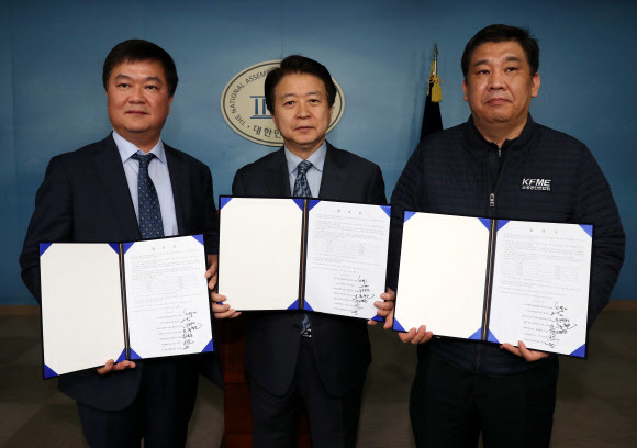 22일 오전 국회 정론관에서 과학기술정보방송통신위원회 노웅래 위원장이 케이티(KT) 아현국사 화재 피해 상인들에 대한 보상금 합의안을 발표하고 관계자들이 합의안을 들어 보이고 있다. 왼쪽부터 케이티 이승용 통신사업협력실장, 노웅래 위원장, 최승재 소상공인연합회 회장. <연합뉴스>