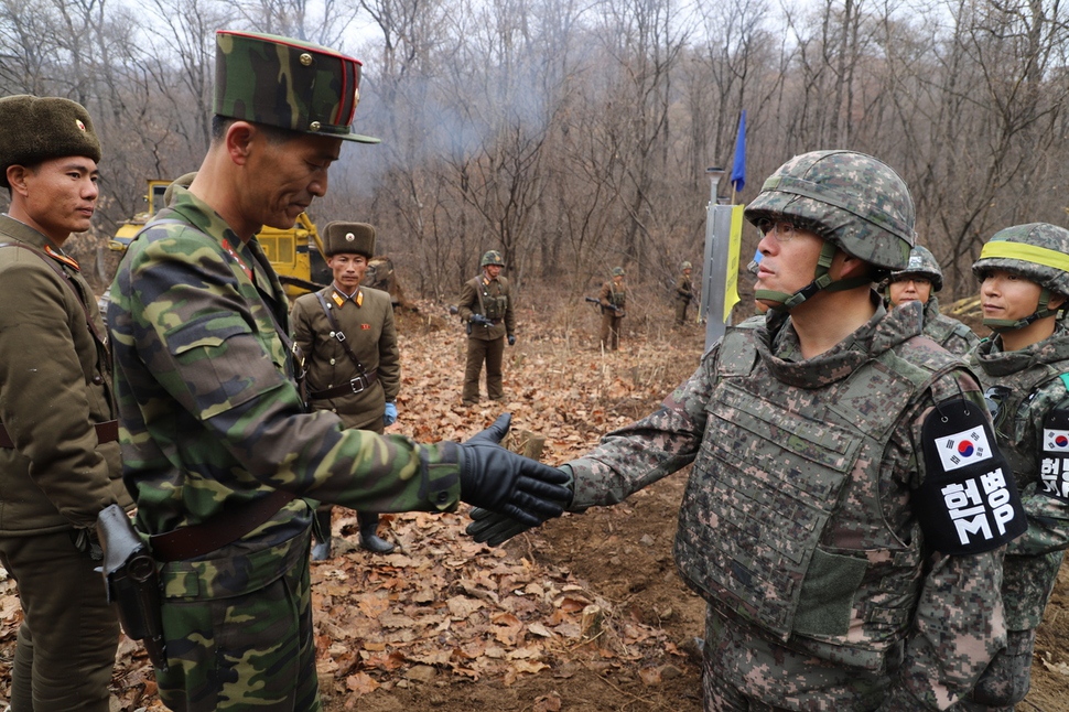 남북은 지난해 11월22일 강원도 철원 비무장지대(DMZ) 화살머리고지에서 공동 유해발굴을 위한 전술 도로를 연결했다. 도로 연결 작업에 참여한 남북 군인들이 군사분계선 근처에서 만나 악수하고 있다. 국방부 제공