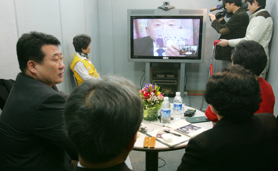 2006년 2월 27일 오전 서울 중구 남산동 대한적십자사에서 열린 남북이산가족 화상상봉에 참가한 북쪽 가족 유창식(화면)씨가 남쪽 가족들에게 가족사진을 보여주고 있다. 사진공동취재단