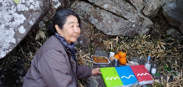 지난 15일 김순이 시인이 남편 고 김종철 선생의 유골을 뿌렷던 한라산 정상부 선작지왓의 탑궤에서 25년만에 개정판으로 복간한 <오름나그네> 1·2·3권을 헌정하고 있다. 사진 김경애 기자