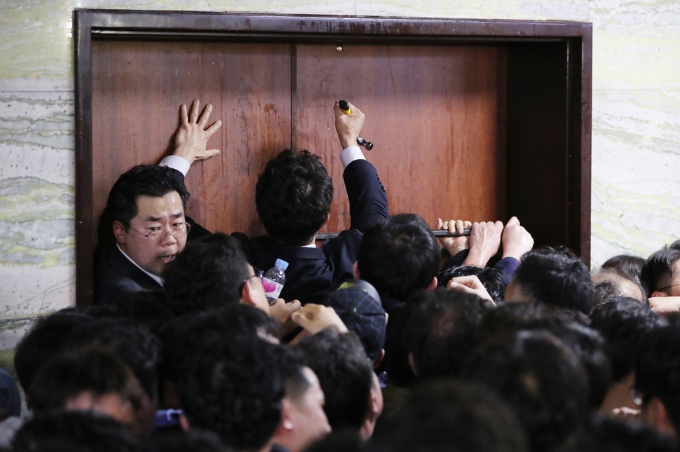 국회 관계자들이 26일 새벽 여야4당의 수사권조정법안을 제출하기 위해 ‘빠루’와 망치를 사용해 자유한국당 당직자들이 점거한 국회 의안과 진입을 시도하고 있다. 연합뉴스