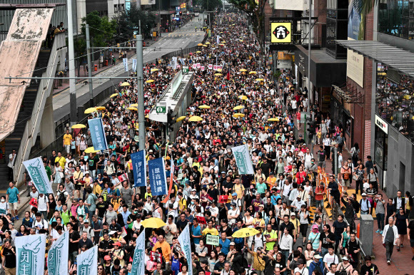 홍콩 시민들이 28일 중국 본토로의 범죄인인도 법안에 반대하는 행진을 하고 있다. 일부는 2014년 ‘우산혁명’의 상징인 노란 우산을 들었다. 홍콩/AFP 연합뉴스