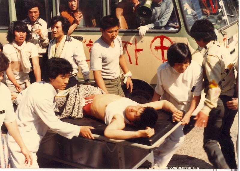 총상을 입은 당시 광주 서석고 3학년 전형문이 시트에 누운 채 이동 중이고, 왼쪽 손목에 수건을 묶은 친구 김동률이 걱정스러운 눈으로 바라보고 있다.(<5·18, 우리들의 이야기> 본문 268쪽)