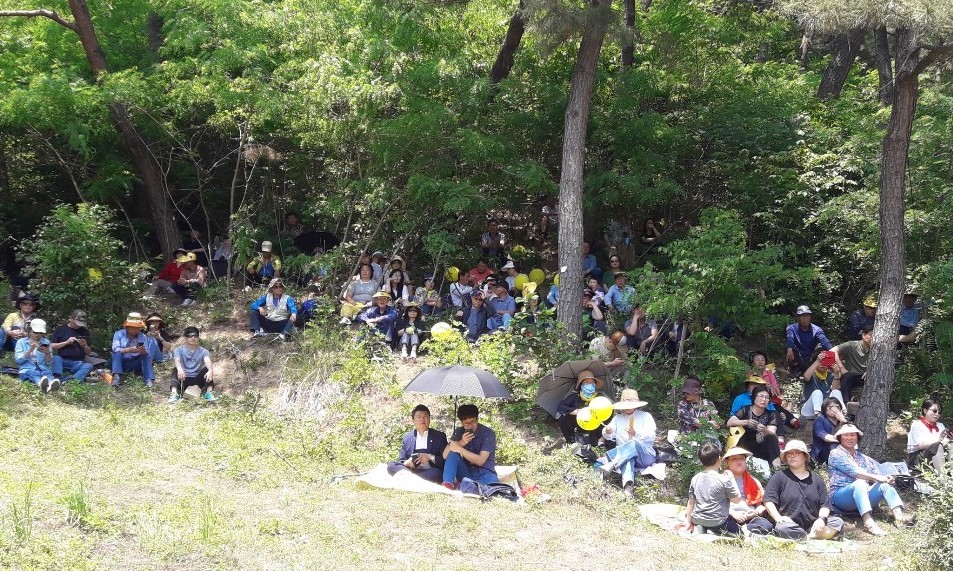 추도식장에 자리를 구하지 못한 추모객들이 주변 산등성이에 둘러앉아 있다.