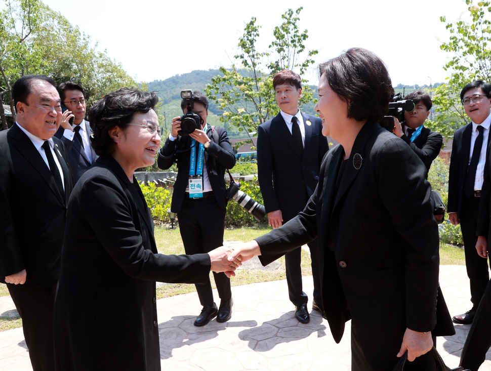 문재인 대통령의 부인인 김정숙 여사(오른쪽)가 23일 경남 김해시 진영읍 봉하마을 대통령 묘역에서 엄수된 노무현 전 대통령 서거 10주기 공식 추도식에 앞서 사저를 방문, 노 전 대통령의 부인 권양숙 여사와 악수하고 있다. 노무현재단 제공