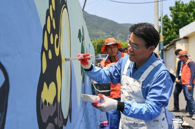 지난 24일 광양제철소 인근 섬거마을에서 최정우 회장이 포스코 재능봉사단원들과 함께 담장에 벽화를 그리고 있다. 포스코 제공