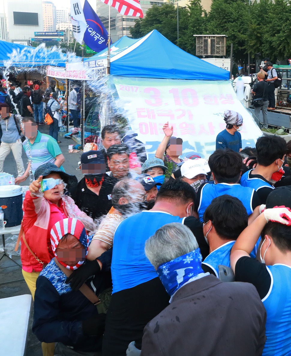 25일 오전 서울 종로구 광화문 광장에서 농성 중이던 대한애국당(우리공화당) 천막을 서울시와 용역업체 관계자들이 철거 작업에 돌입하자 당원들이 물을 뿌리고 몸싸움을 벌이며 저항하고 있다. 서울시는 오전 5시 20분부터 천막 2동 등 불법 설치물에 대한 행정대집행을 실시 중이다. 대한애국당은 24일 당명을 ‘‘우리공화당‘‘으로 개정했다. 연합뉴스