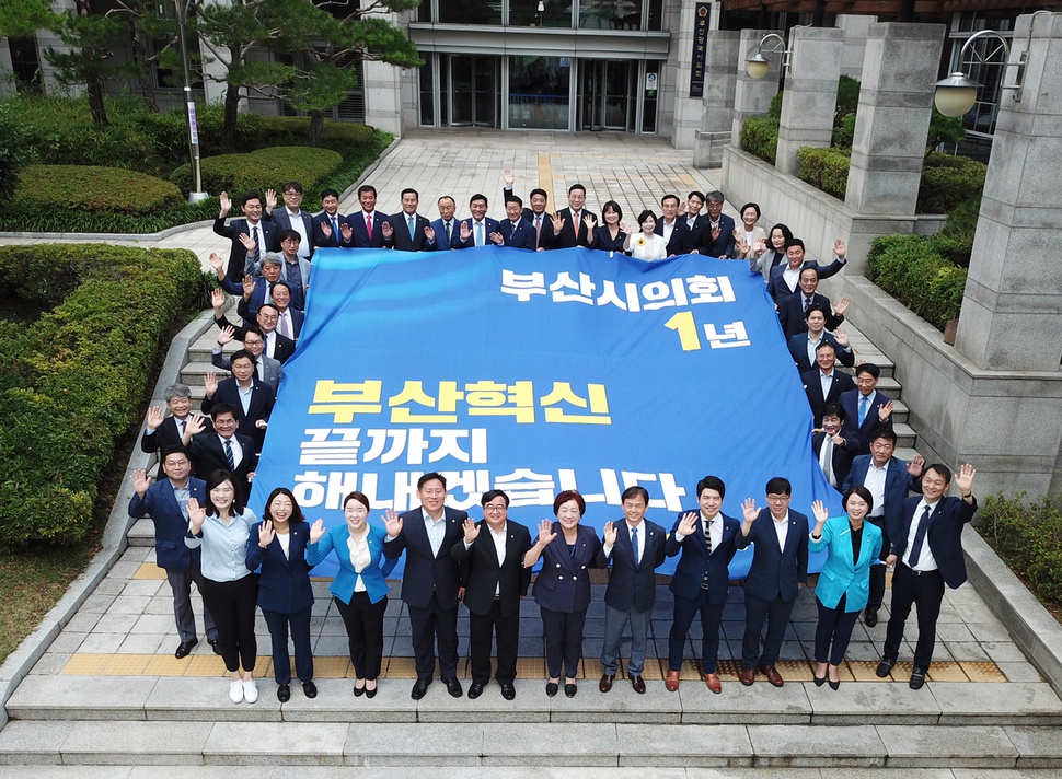 부산시의회 의원들이 8대 의회 1주년을 맞아 부산시의회 건물 앞에서 지속적인 혁신을 다짐하며 손을 흔들고 있다. 부산시의회 제공