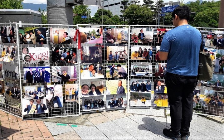노회찬 전 정의당 원내대표 1주기 추모문화제에 참석한 시민이 고인의 사진을 살펴보고 있다.