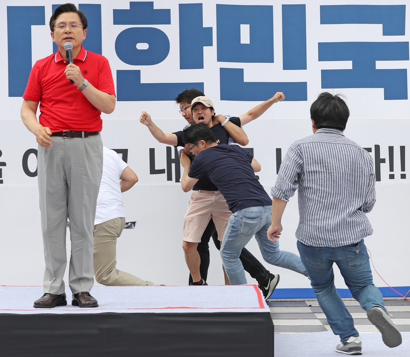 24일 오후 서울 종로구 세종문화회관 앞에서 열린 문재인 대통령 규탄 집회에서 황교안 자유한국당 대표 발언 때 무대 위로 올라간 장애인단체 회원이 당 관계자들에게 저지당하고 있다. 연합뉴스