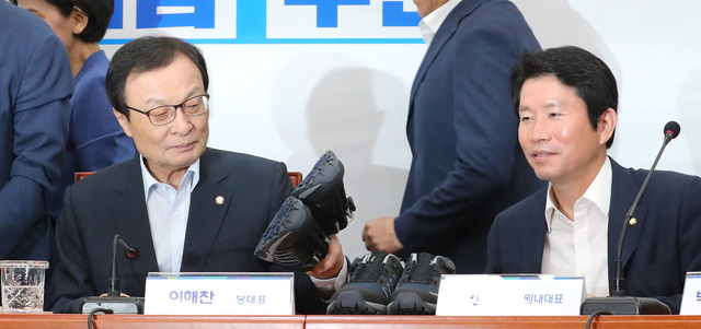 더불어민주당 이해찬 대표(왼쪽)가 지난 23일 오전 국회에서 열린 당대표-최고위원 취임1주년 공동 기자회견에 참석해 열심히 뛰자는 취지로 신발을 만져보고 있다. 오른쪽은 이인영 원내대표. 연합뉴스
