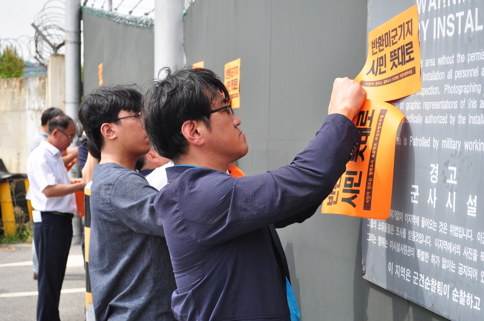 3일 의정부평화포럼 회원들이 경기 의정부에 자리한 캠프 레드클라우드 벽에 ‘반환 미군기지를 시민 뜻대로 이용하도록 하자’는 내용의 벽보를 붙이고 있다.