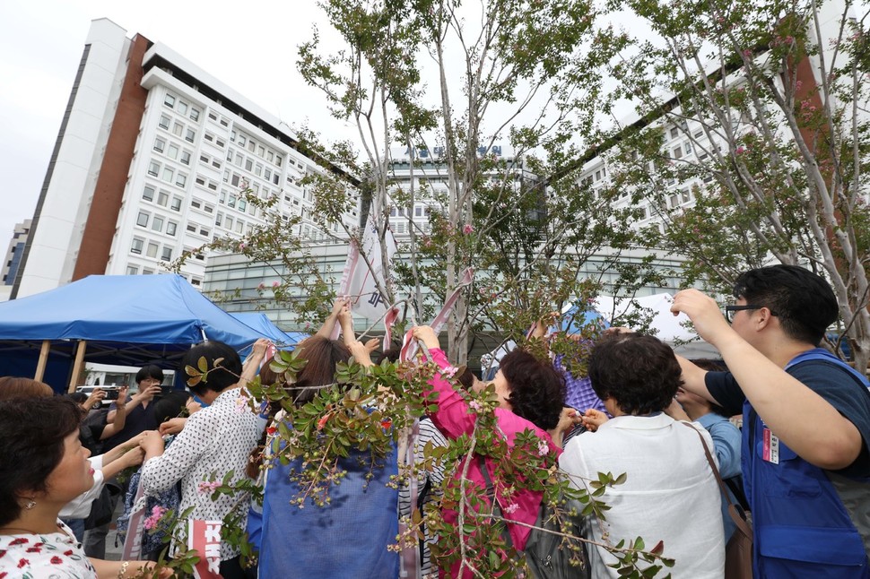 정규직 전환이 확정된 서울대병원 비정규직 노동자들이 4일 오후 서울 종로구 서울대병원 본관 앞에서 천말농성 해단식을 마친 뒤 천막 옆 나무에 걸려있던 ‘직접고용 쟁취’ 손팻말을 풀고 있다. 백소아 기자