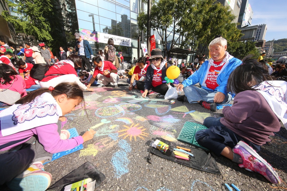 2016년 9월에 열린 ‘서리풀 축제’에서 어린이와 성인들이 서울 강남구 반포대로 아스팔트 도로 위에서 분필로 그림을 그리고 있다. 서초구는 당시 경찰과의 별도로 협의하에 차량을 통제했다. 서초구 제공.