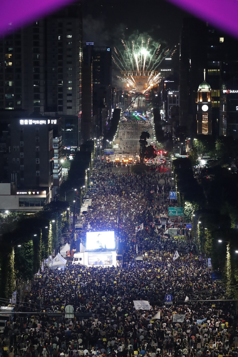 지난 28일 서울 서초구 서초역부터 예술의전당 방향 서초3동 사거리에서 서래풀 페스티벌 폐막행사가 열려 불꽃레이저쇼가 펼쳐지는 동안(사진 윗쪽),  ‘제7차 사법적폐 청산을 위한 검찰개혁 촛불문화제’ 에 참가한 시민들이 촛불을 들어올리며 검찰 개혁을 촉구하는 구호를 외치고 있다. 이정아 기자