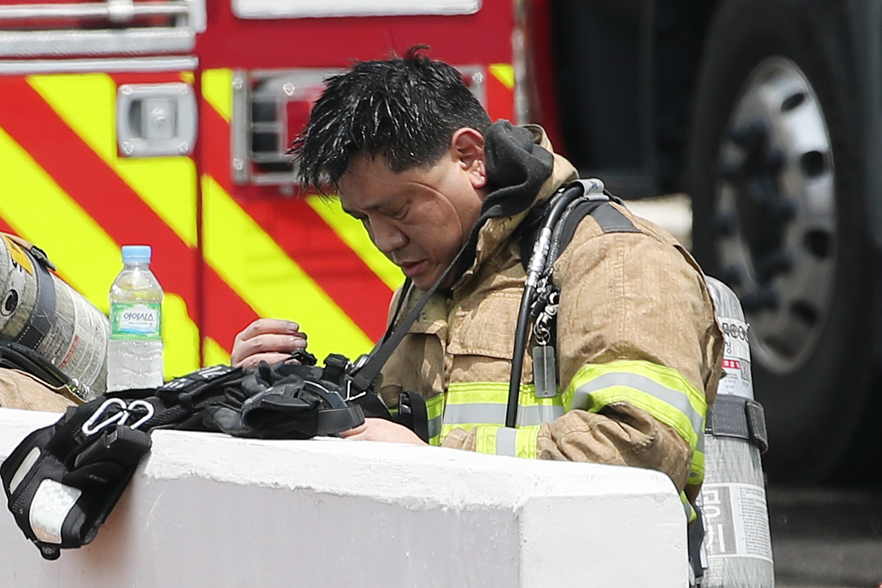  21일 오전 화재가 발생한 경기 용인시 처인구 양지면 SLC 물류센터에서 교대를 마친 소방대원이 보호구를 벗고 있다. 연합뉴스